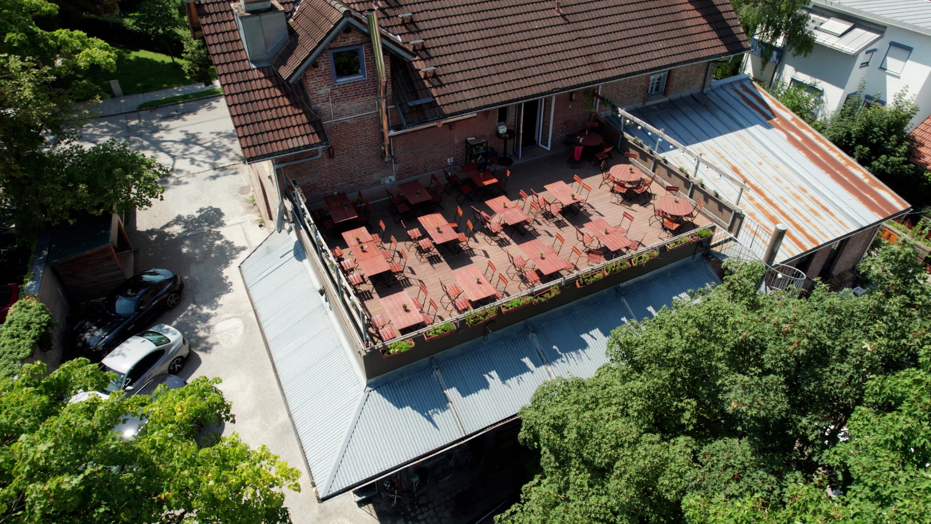 Luftaufnahme der Dachterrasse mit Holztischen und Außenbereich im Obergeschoss